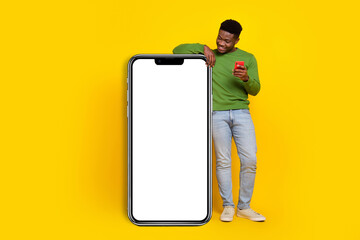 Full length photo of young curious man charring with friends see big long phone isolated on yellow color background
