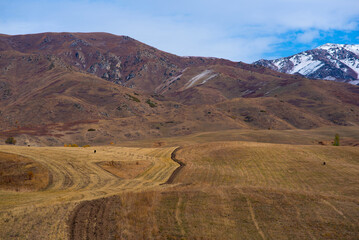 Obraz premium Agricultural areas in the Himalayan foothills in autumn colors. Valley of mountains. High mountains with snow-capped peaks on the background. Beautiful mountain landscape.