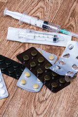Fototapeta na wymiar Pile of pills and syringe on wooden background