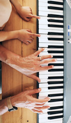 Fototapeta premium Piano, top view and hands of kid learning with father in home, playing or bonding together. Development, education or parent teaching child how to play music instrument, acoustic or electric keyboard