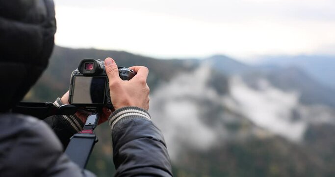 Male photographer takes pictures with digital camera in mountains