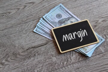 Money and chalkboard with text MARGIN. Business concept
