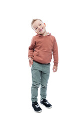 Smiling boy is standing. A cute blond man with a trendy hairstyle in a brown hoodie and gray trousers. Joy and positivity. Full height. Isolated on white background. Vertical.