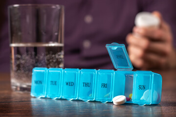 Pill organizer with variety of pills and supplement. Weekly Pill Organizer on the table.