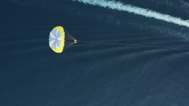 Aerial view of a person doing parasail with a motorboat along the coast in Sicily, Italy.