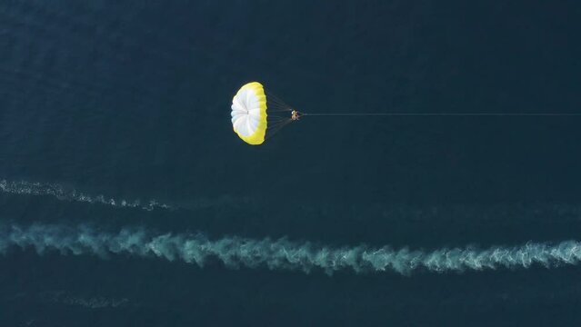 Aerial view of a person doing parasail with a motorboat along the coast in Sicily, Italy.