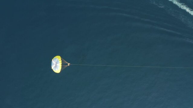 Aerial view of a person doing parasail with a motorboat along the coast in Sicily, Italy.