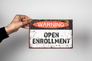 Open Enrollment. Warning sign with text on a white background in a woman's hand