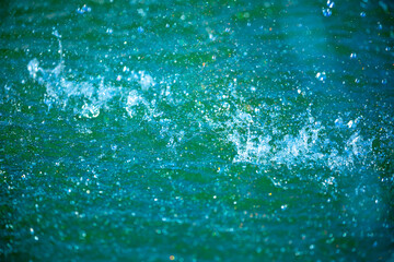 Water background, blue sea water. Beautiful texture of sun glare on the water and sea foam.