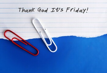 Two office paper clip on a lined sheet note with text written THANK GOD IT'S FRIDAY on background  - Concept of corporate employee who need a weekend rest  after hard weekday works