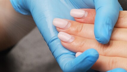 Manicurist sprays antiseptic on the nails before treating old  acrylic nails. Treatment of nails with a disinfectant before manicure. Applying a disinfectant to women's hands.