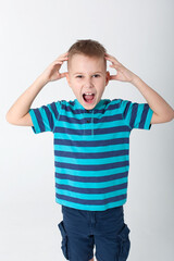 handsome boy looks angry. The child is offended, threatens, shows a fist. Angry, resentful, aggressive child. Portrait on white studio background. Children's human emotions concept.