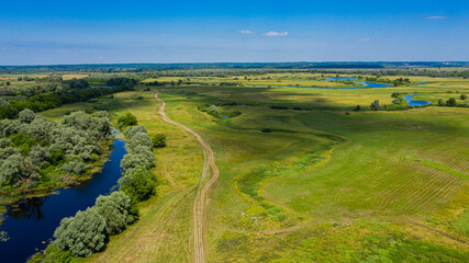 Fototapeta na wymiar Wide green valley with a small river . Green meadows. Top view over beauty nature. Aerial view of a beautiful summer hilly landscape.