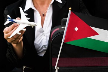 business woman holds toy plane travel bag and flag of Jordan
