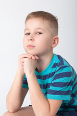 handsome boy looks angry. The child is offended, threatens, shows a fist. Angry, resentful, aggressive child. Portrait on white studio background. Children's human emotions concept.