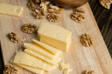 Sliced hard cheese with holes and walnuts