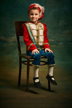 Portrait of cute little boy dressed up as medieval character, little prince and pageboy posing over dark vintage style background, Fashion, emotions, theater art concept