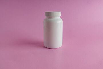 A jar for medicine on a pink background.