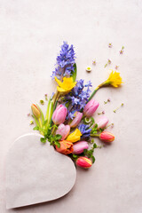 Colorful bouquet of spring flowers with heart shape for mother's day greetings. Vertical background for greeting card and banner. Top view with space for text.