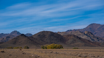 Rocky desert landscape with sparse vegetation and mountains peaks in a blue haze. Typical landscape near at Nepal Tibet border. Flat dry desert with mountains.