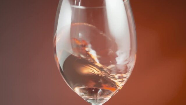 Close up of rose wine waving inside a wineglass. Slow motion. 