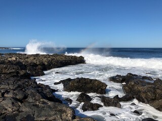 Ocean view background. Water splash from waves on rocky beach. Lanzarote island horizontal wallpaper.