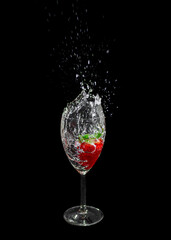 Strawberry in a glass. Water splashes out of the glass after throwing the strawberry. Champagne with a strawberry.