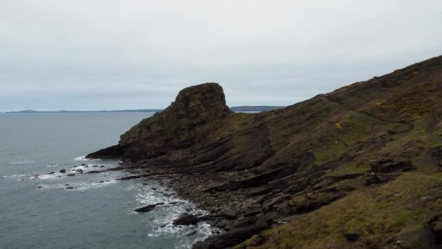 Pushing Aerial Drone Towards Rickets Head with Coast Path and Crashing Waves from Atlantic Ocean in Pembrokeshire UK 4K