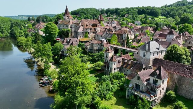 Small, medieval village situated next to a river, flowing through a rich forest in the heart of France. Droneshot flies over the village, showing medieval brick buildings, and walls overgrown by ivy.