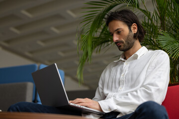 portrait d'un jeune homme employé de bureau ou homme d'affaires qui travaille sur un ordinateur portable, assis dans un bureau confortable