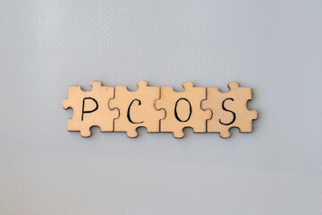 Polycystic Ovarian Syndrome. Hand Writing PCOS on wooden puzzles on a blue background