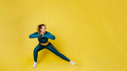 Fototapeta na wymiar A woman does fitness exercises for a slim body and youth on a yellow background. Willpower and body. The path to health and beauty. Advertising for fitness centers, gyms, individual trainers.