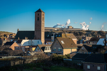 Dutch village Wijk aan Zee on the coast of the North Sea, view of the church and heavy industry in...