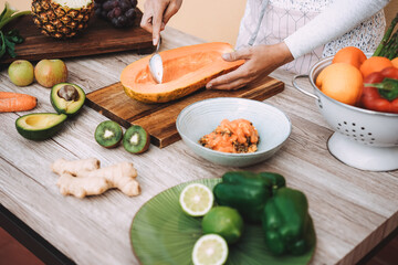Young woman preparing healthy fruit salad outdoor - Focus on right hand holding papaya