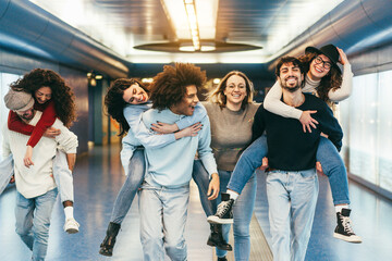 Happy friends having fun inside underground metropolitan station - Soft focus on girl hugging...