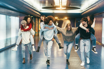Happy friends having fun inside underground metropolitan station - Soft focus on center girl face