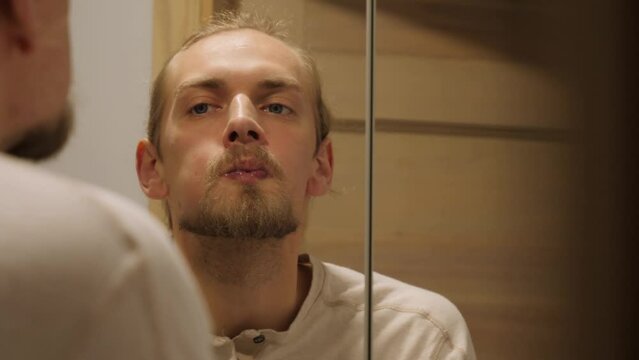 Man with braces rinse teeth looking into mirror.