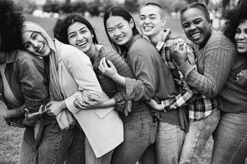 Young multiracial women having fun laughing together outdoor - Focus on african girl face - Black and white editing