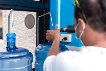 Using a heat gun to tighten the plastic seal on the cap lid of a clear HPDE water container. A purified water refilling station business.