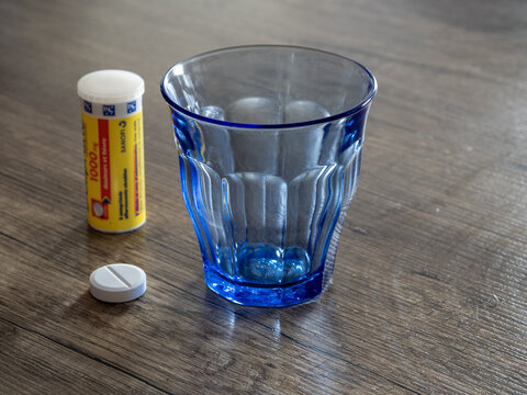 Doliprane paracetamol placed next to a bleu glass. Acetaminophen prepared in advance on a table. Wait for water to take medication. To prepare treatment.
