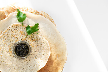 served pancake with black caviar, parsley