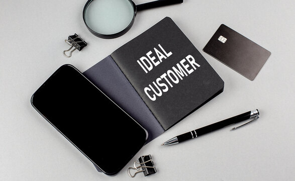 IDEAL CUSTOMER text written on black notebook with smartphone, magnifier and credit card