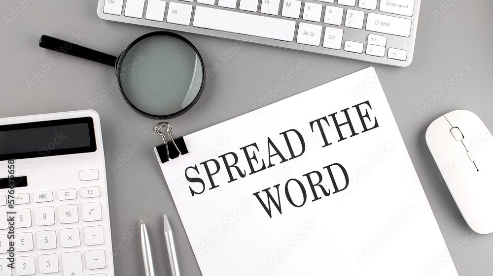 Poster spread the word written on paper with office tools and keyboard on the grey background