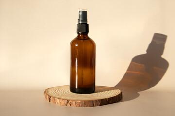 Brown glass bottle with spray moc ap on a beige background on a wooden catwalk in the sun.