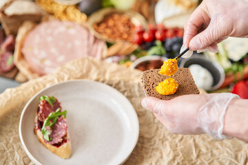 The waiter makes bruschetta or tapas. Table full of mediterranean appetizers, tapas or antipasto. Assorted Italian food set. Delicious snack on party or picnic time. Italian style banquet. 