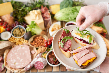 The waiter makes bruschetta or tapas. Table full of mediterranean appetizers, tapas or antipasto. Assorted Italian food set. Delicious snack on party or picnic time. Italian style banquet. 