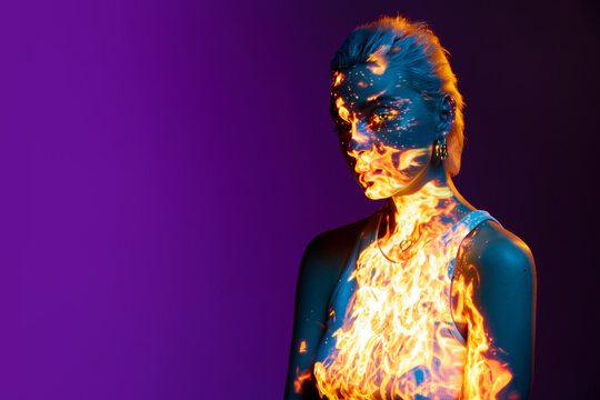 Robot. Portrait of young blonde girl with digital burning fire on body posing over purple background in blue neon lights. Concept of art, modern style, cyberpunk, futurism and creativity