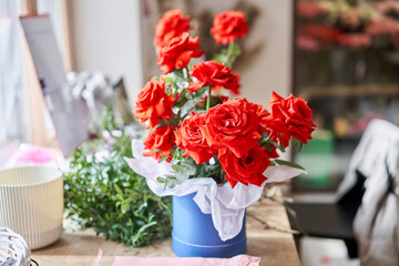 Red rose. Young woman making fashion modern bouquet in round blue box. Colorful color mix flower. Floral shop concept. Flowers delivery