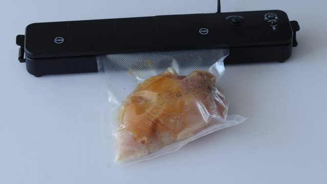 The evacuator removes air from the bag of raw spiced chicken breast. It then seals the bag.