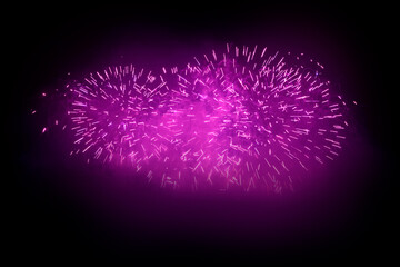 Beautiful pink fireworks display lights up the sky with dazzling display during New Year celebration. Abstract colored fireworks background with copy space. Celebration and anniversary concept
